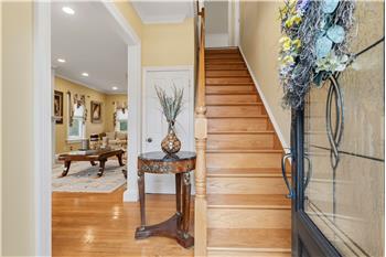 Foyer entry featuring wood-finish flooring, staircase with a natural wood handrail, recessed lighting, and a front door with lea