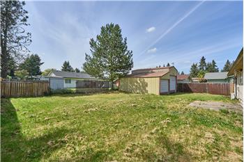 Fully Fenced Backyard with View of the Patio and Detached Garage.