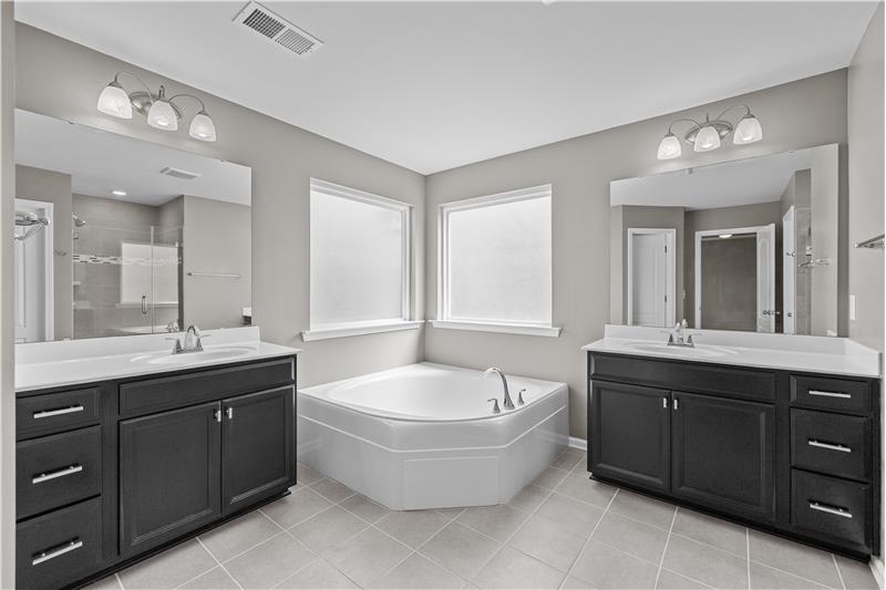 Large en-suite, primary bath featues two vanities and an oversized soaking tub framed by two picture windows, large walk-in clos