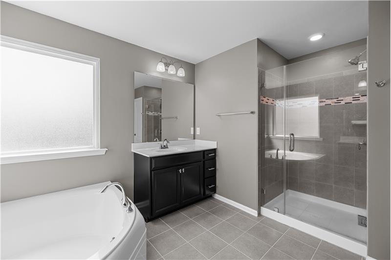 Beautiful frameless glass shower with custom tile accents adds a modern touch to the primary bath