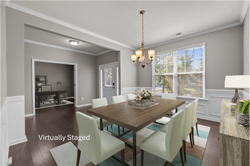 Elegant dining room with rich hardwood floors, detailed wainscoting, and crown molding accents.