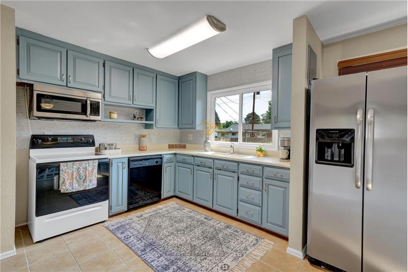 The eat-in Kitchen features tile floors & a smooth top range oven, black dishwasher, SS built-in microwave, & refrigerator
