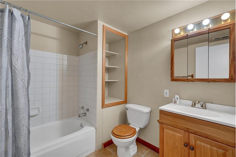 The Basement Bathroom has a vanity, built-in medicine cabinet, and tub/shower