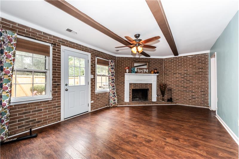 Finished basement with new luxury vinyl plank flooring, masonry fireplace with mantel, brick walls.