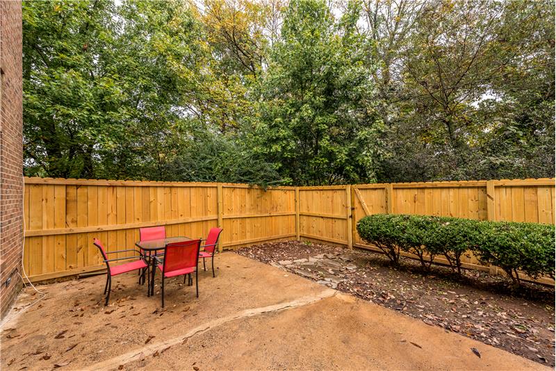Spacious, private patio with brand new fencing and landscaping surrounded by mature trees.