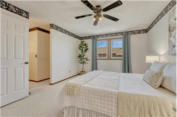 The spacious primary suite features a lighted ceiling fan, walk-in closet, & a private en-suite bathroom.