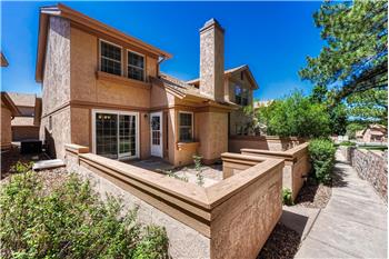 Front of home with enclosed courtyard, surrounded by peaceful, lush green spaces, mature trees, and shrubs.