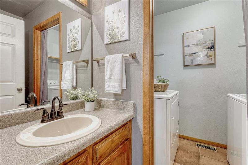 The powder bathroom has a vanity and mirror and entrance into the laundry room with washer and dryer that stay.