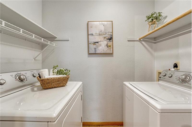Laundry room with tile flooring, built in shelves, and washer/dryer included.