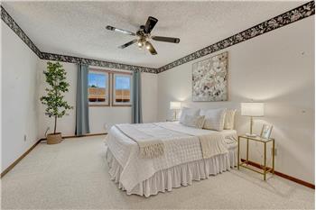 The spacious upper level primary bedroom is a private retreat that features neutral carpet and a lighted ceiling fan.