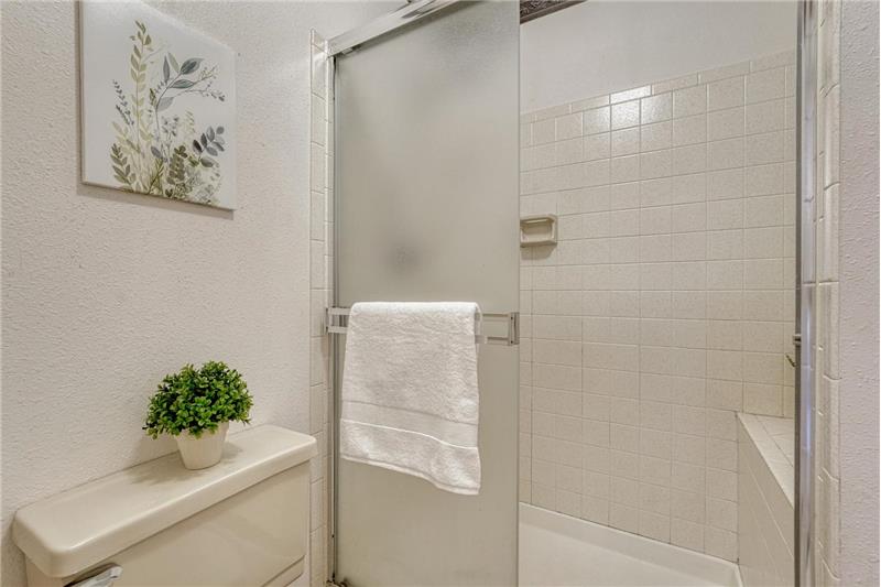 Primary bathroom with tiled shower and built-in seat.
