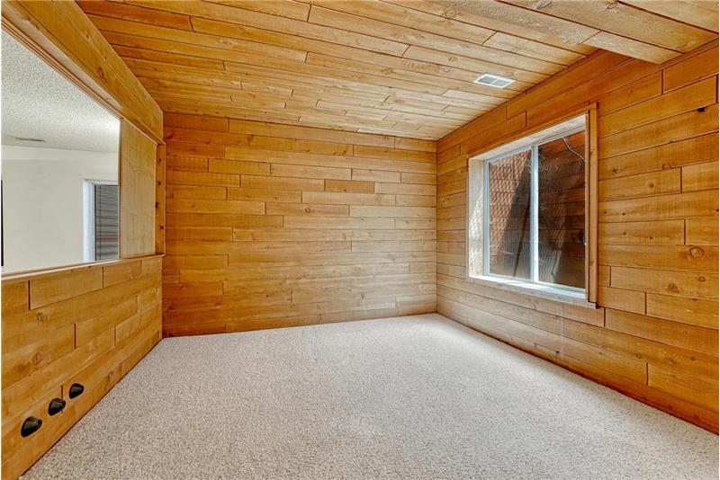 Basement bedroom #3 has wood paneled walls and ceiling.