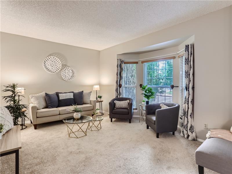 The relaxing living room opens to the dining room and front yard via this lovely bay window.