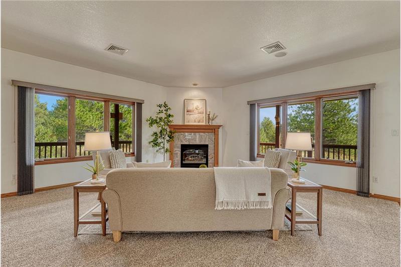 Great room with gas fireplace, neutral carpet, and in-ceiling speakers.