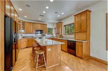 Kitchen with plentiful cabinets, granite counters and hardwood flooring.
