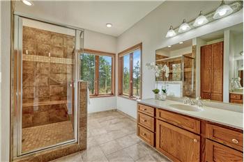 Primary bath with tile flooring two separate sink vanities, and a large walk-in shower.