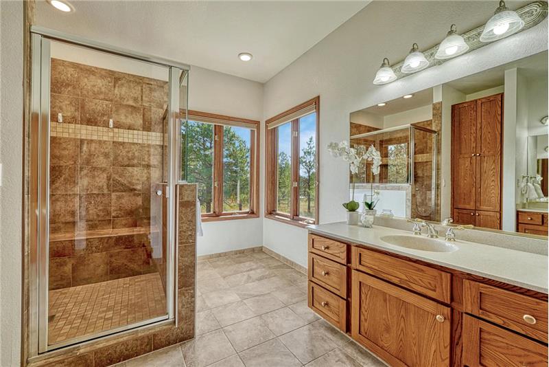 Primary bath with tile flooring two separate sink vanities, and a large walk-in shower.