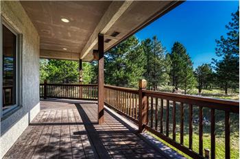 Covered wraparound wood deck along the back and side of the home.