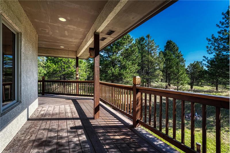 Covered wraparound wood deck along the back and side of the home.