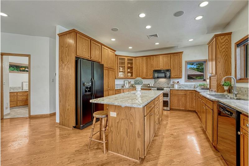 Spacious kitchen with abundant storage, roll out shelving, recessed lighting, granite counters, and cabinet pantry.