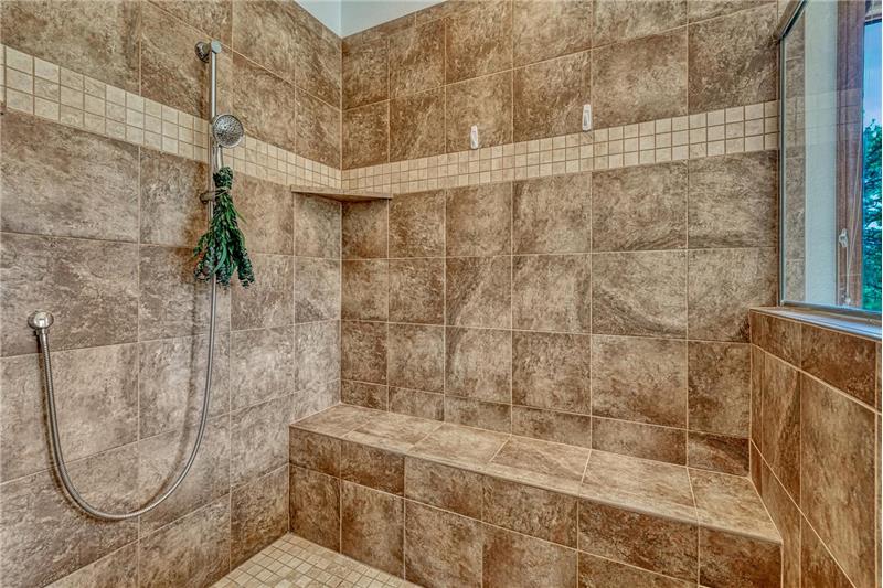 Oversized tile shower with bench seat and a mud set tiled shower pan.