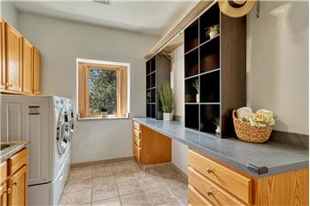 Laundry has built-in cabinets and a long folding counter.