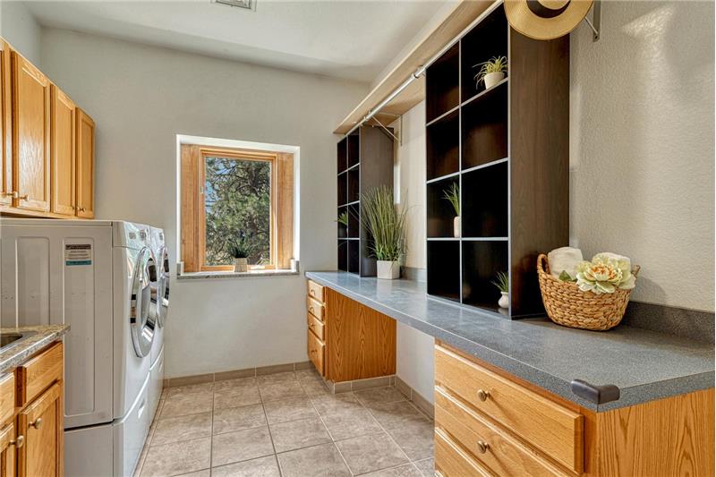 Laundry has built-in cabinets and a long folding counter.