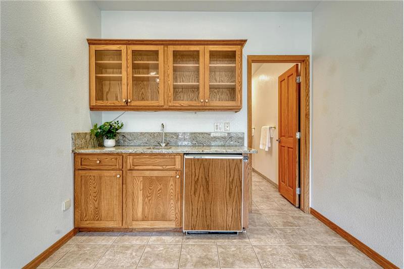 Wet bar with granite counters and beverage fridge.