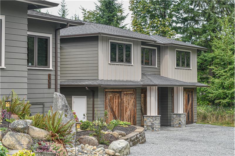 Side of home showcasing the three-car garage with custom doors and the bonus room above.