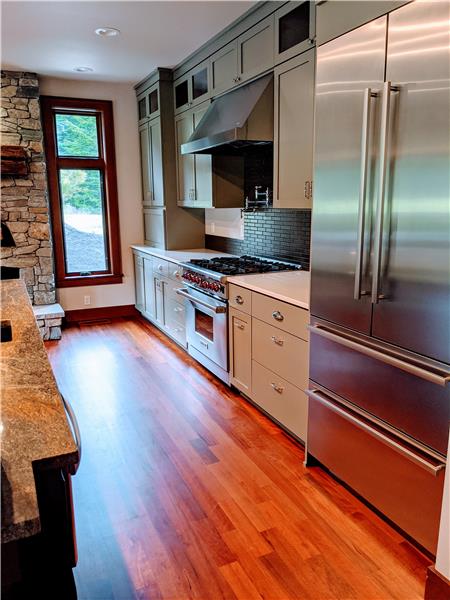 Four-door, counter depth Liebherr refrigerator, Wolf gas stove and range with pot-filler. Subway tile backsplash is porcelain. 