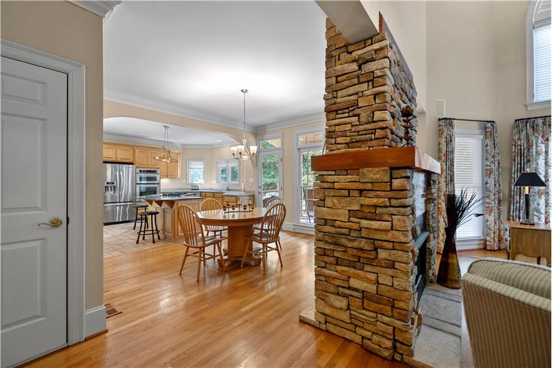 Double-sided stacked stone fireplace with wood mantel separates the breakfast area and great room.