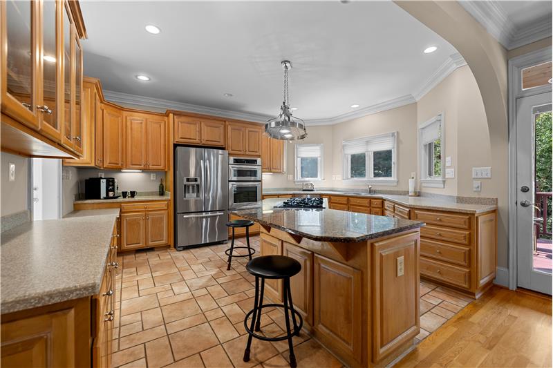 Kitchen: custom cabinets, tile floors, island with granite, solid surface counters, stainless steel appliances, gas cooktop.