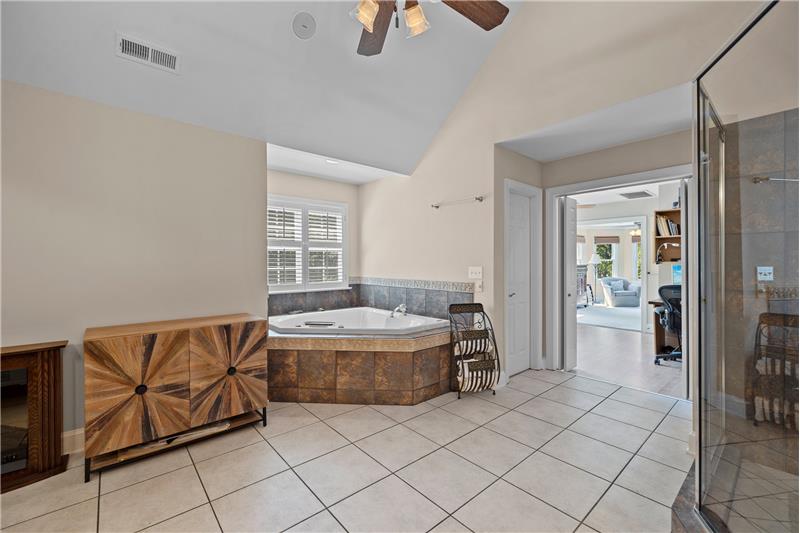 Primary bathroom features deep whirlpool tub, tile floor, tile surround, private water closet.
