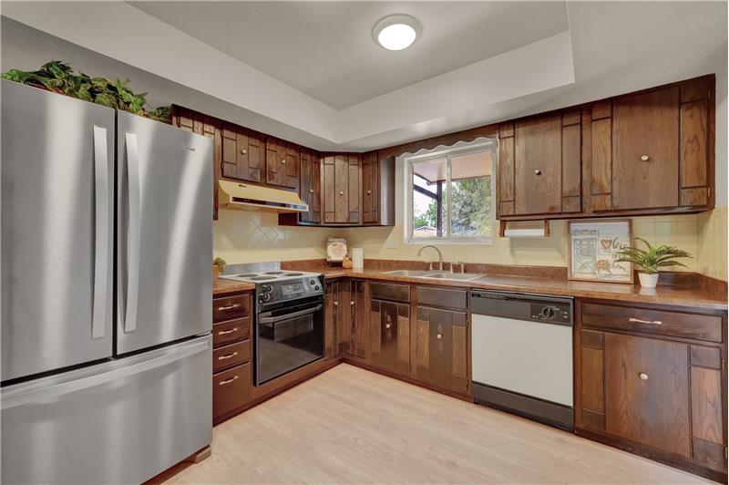 Kitchen includes cabinets w/laminate countertops, electric range oven w/vent hood, dishwasher, & French door refrigerator
