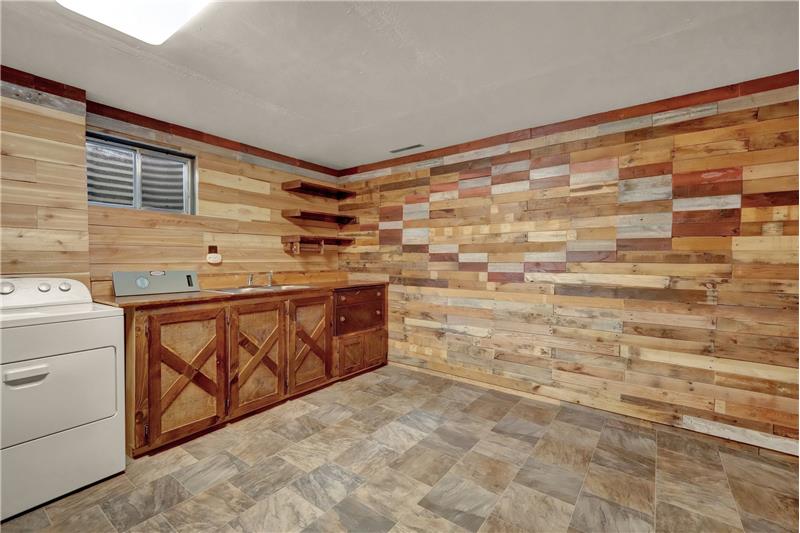 The laundry/storage room has wood plank walls & attractive new linoleum floors