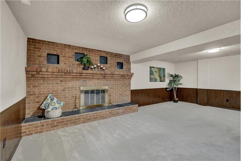 The basement Family Room features a wood burning fireplace with brick surround and raised hearth