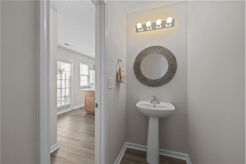 Powder room behind the kitchen features pedestal sink and pretty mirror.