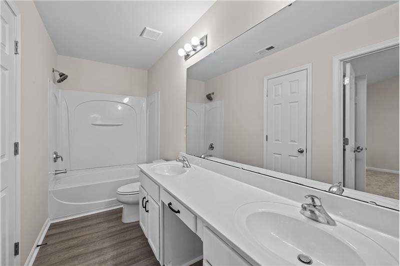 En-suite bathroom with double sink vanity, linen closet, walk-in closet, mirrored medicine cabinet.