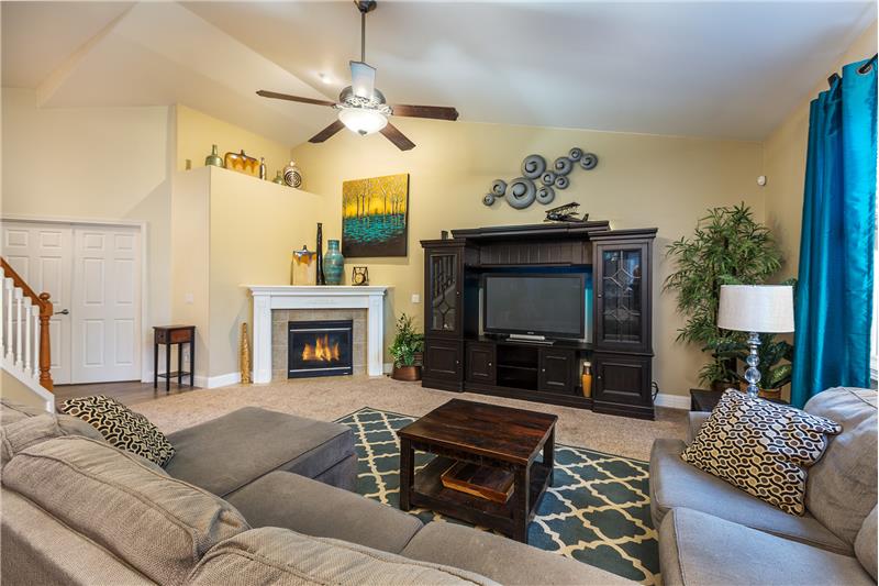 Huge, Cozy Living Room with Vaulted Ceilings, White Mantle and Tile Surround Gas Fireplace and Ceiling Fan.