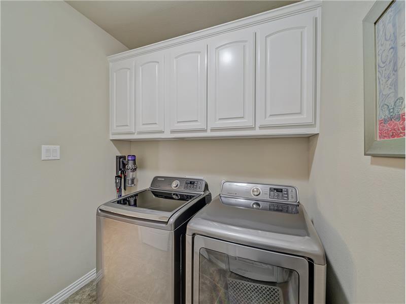 Separate laundry room with cabinets for storage