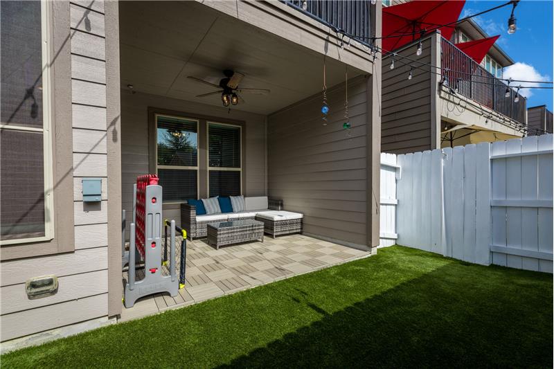 Covered tiled patio and yard with artificial turf.