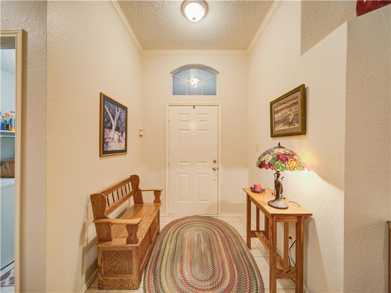 Entryway with light tile flooring, crown molding, and a textured ceiling