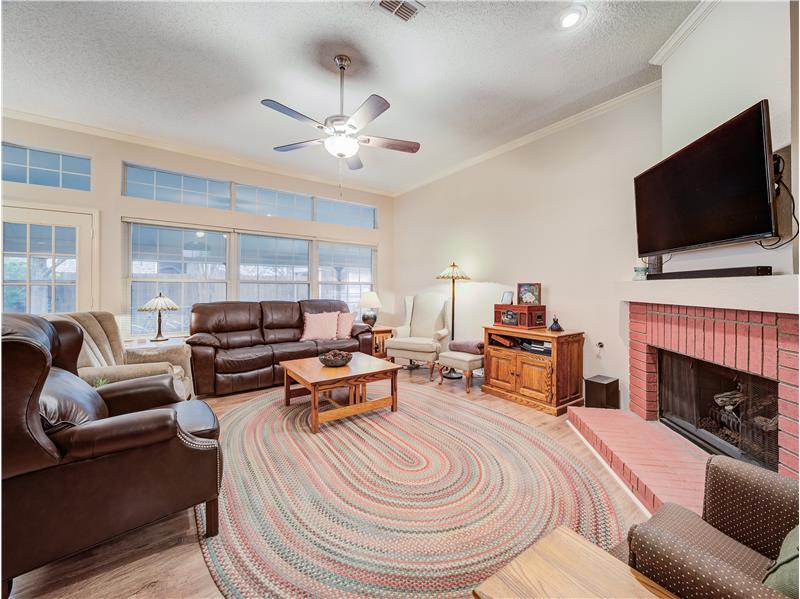 Living room with light hardwood / wood-style floors, crown molding, a wealth of natural light, and a brick fireplace