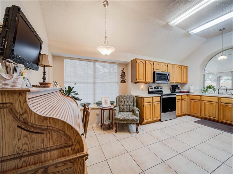 Kitchen with stainless steel appliances, lofted ceiling, sink, pendant lighting, and light tile floors