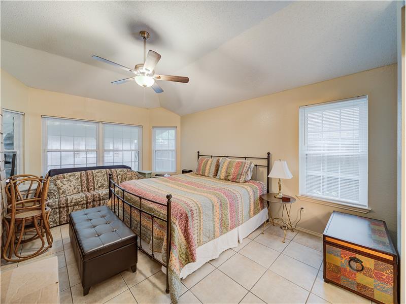 Tiled bedroom featuring lofted ceiling, ceiling fan, and multiple windows