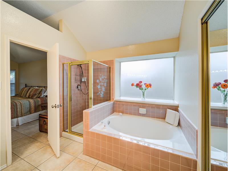 Bathroom featuring vaulted ceiling, plenty of natural light, separate shower and tub, and tile floors