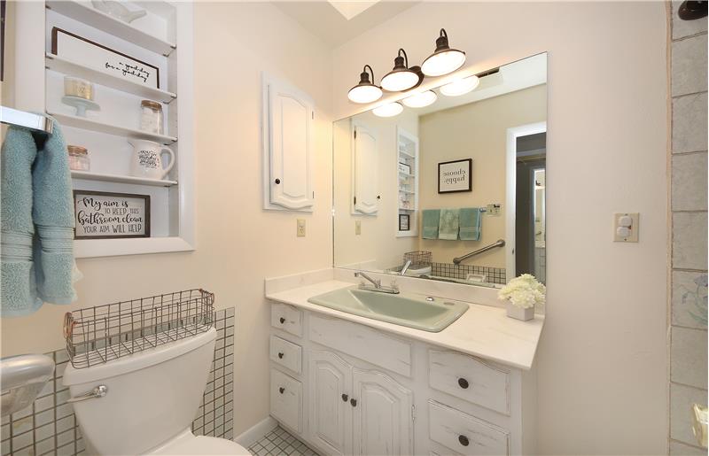 Full bath on main level with large vintage sink, built in shelving, and medicine cabinet