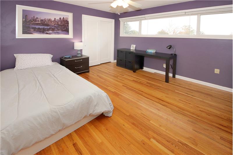 Bedroom 2 with large windows, hardwood flooring, and ceiling fan