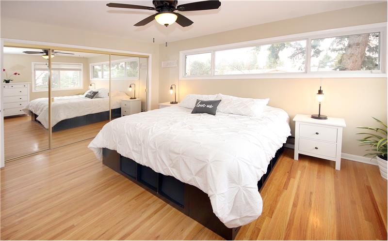 Bright master bedroom with hardwood flooring and ceiling fan