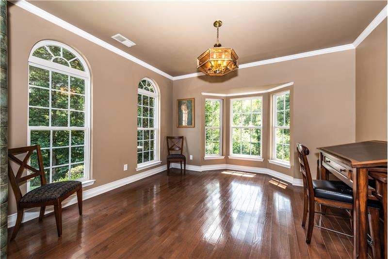 Formal living room features hardwood floors, bay window, great natural light, palladium window accents, crown molding.